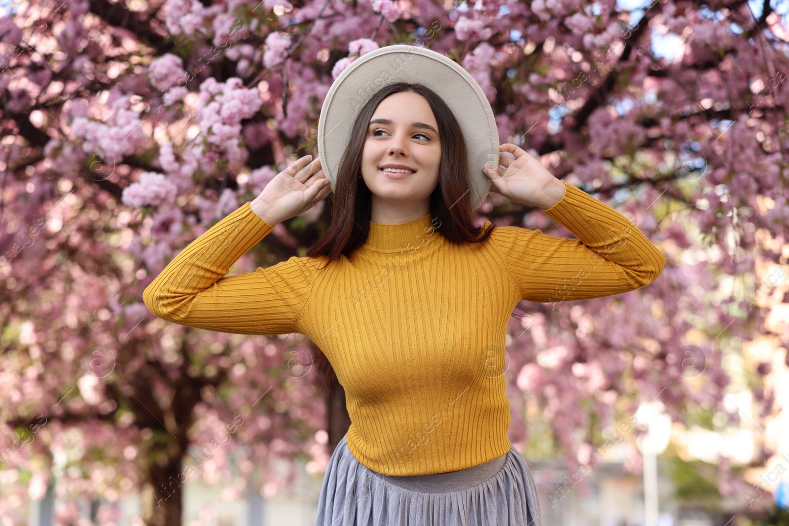 Photo of Beautiful woman in hat near blossoming tree on spring day