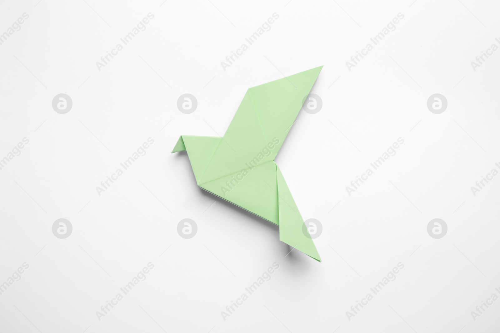 Photo of Beautiful light green origami bird on white background, top view