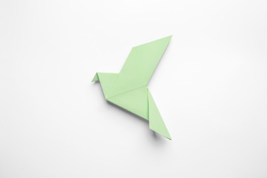 Photo of Beautiful light green origami bird on white background, top view
