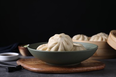 Delicious bao buns (baozi) in bowl on grey table, closeup