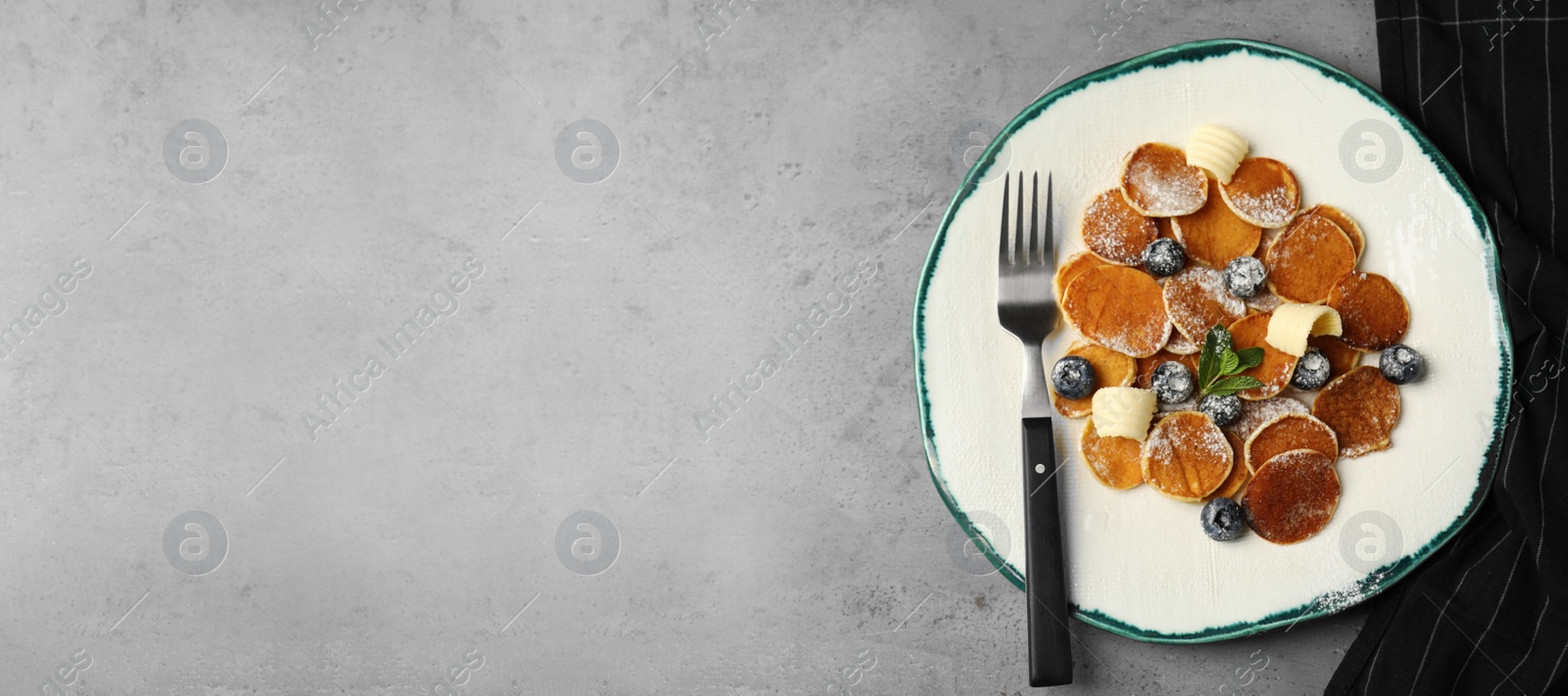 Photo of Cereal pancakes with blueberries and butter on light grey table, flat lay. Space for text