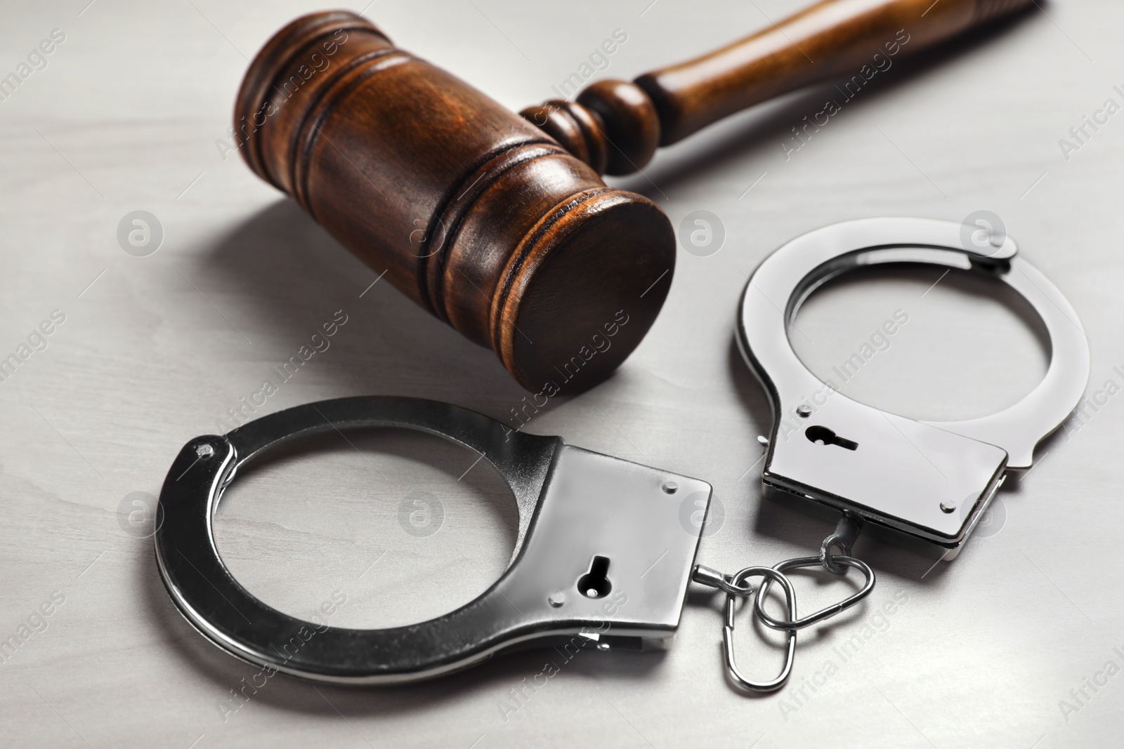 Photo of Judge's gavel and handcuffs on white wooden background. Criminal law concept