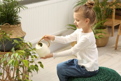 Photo of Cute little girl watering beautiful green plant at home. House decor
