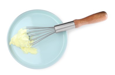 Photo of Balloon whisk with yellow cream and plate isolated on white, top view