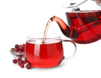 Photo of Pouring delicious cranberry tea from teapot into cup isolated on white