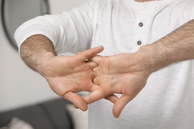 Photo of Man cracking his knuckles on blurred background, closeup. Bad habit