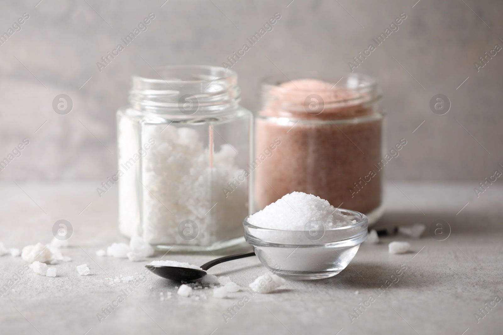 Photo of Different natural salt on grey table, closeup