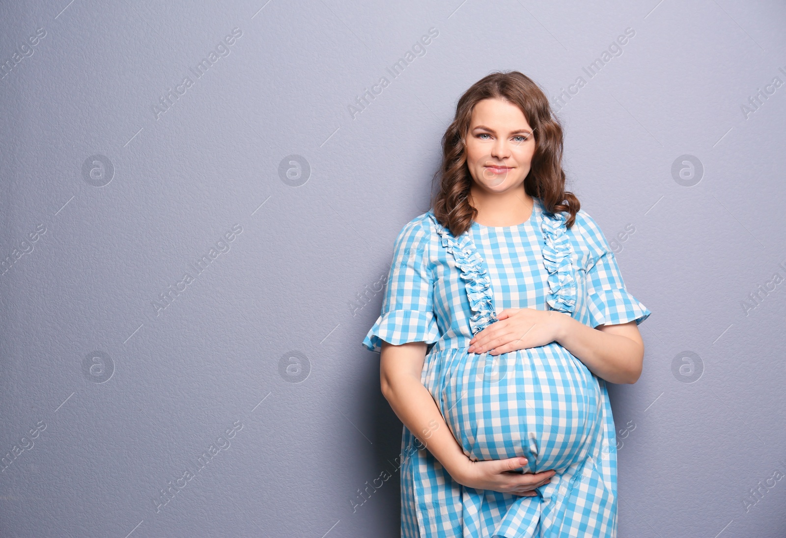 Photo of Young pregnant woman in casual clothes on grey background