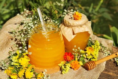 Photo of Delicious fresh honey and beautiful flowers on wooden table