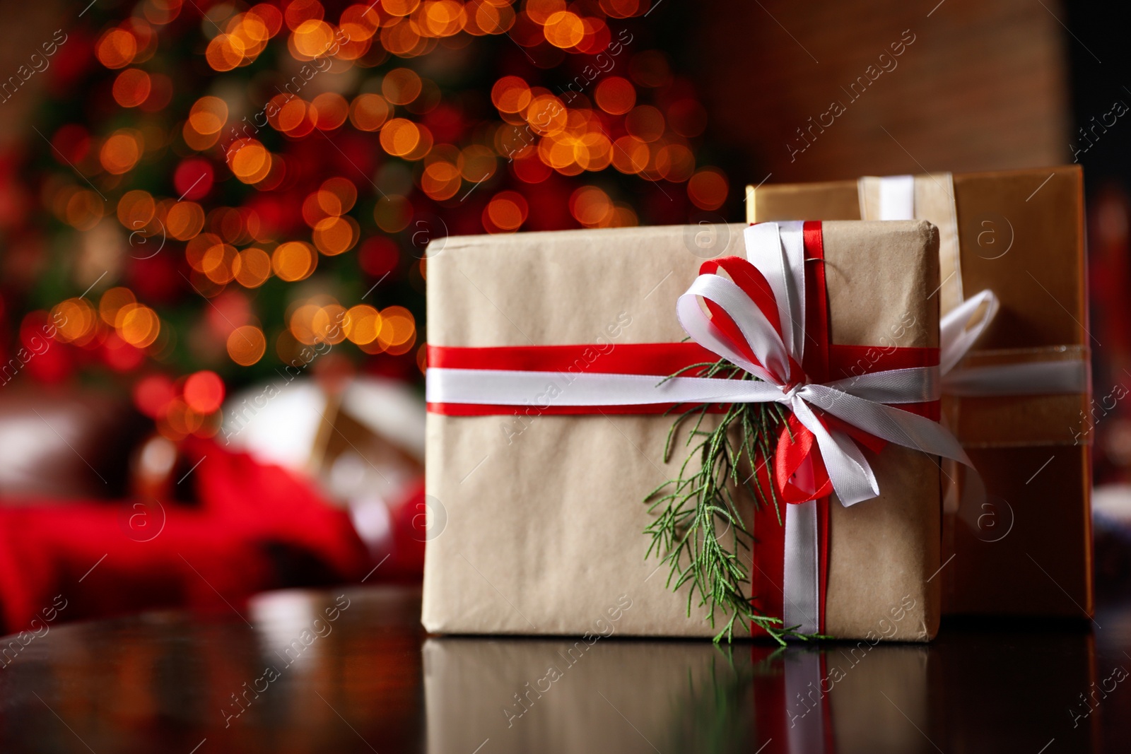 Photo of Christmas gifts on table against blurred festive lights