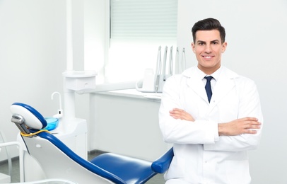 Photo of Portrait of professional male dentist in clinic. Space for text