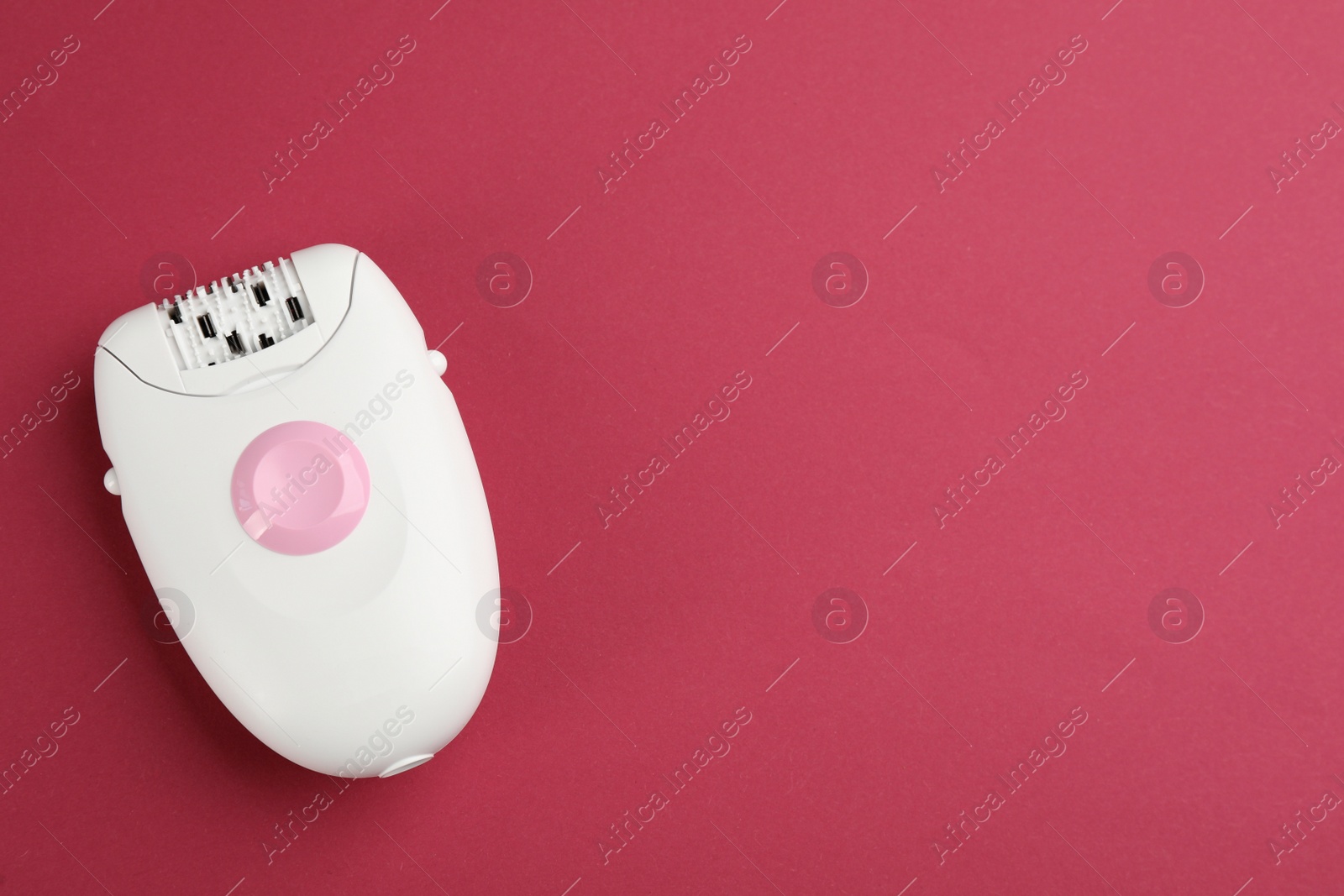 Photo of Modern epilator on crimson background, top view. Space for text