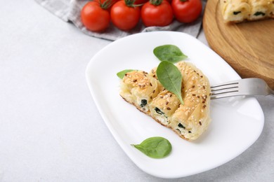 Photo of Piece of delicious puff pastry with spinach on light table