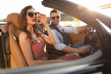 Stylish couple driving luxury convertible car outdoors