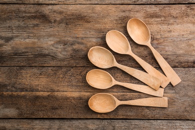 Clean empty spoons on wooden background, top view. Space for text