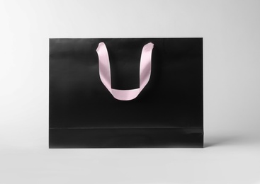 Paper shopping bag with ribbon handles on white background. Mockup for design