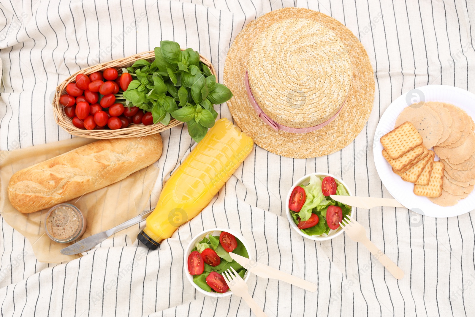 Photo of Juice and food on white striped blanket, flat lay. Picnic season