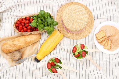 Photo of Juice and food on white striped blanket, flat lay. Picnic season