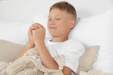 Photo of Boy with clasped hands praying in bed