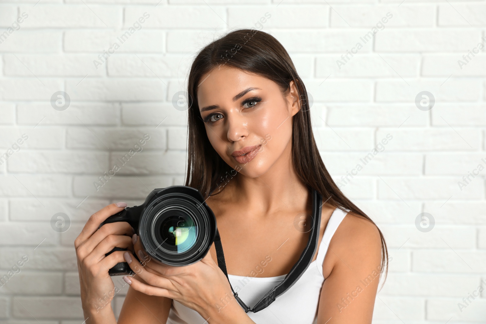 Photo of Professional photographer working near white brick wall in studio