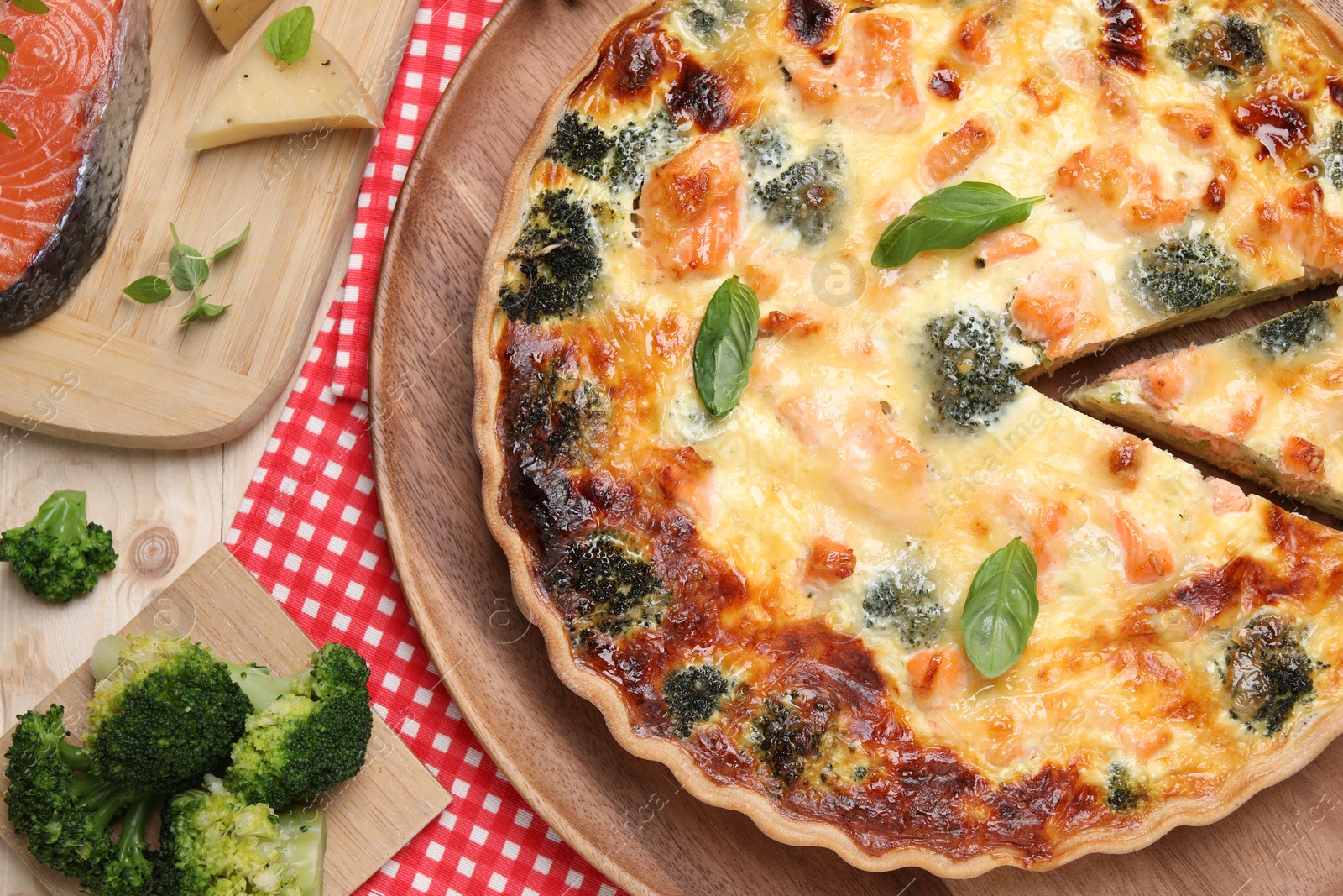 Photo of Delicious homemade quiche and ingredients on table, flat lay