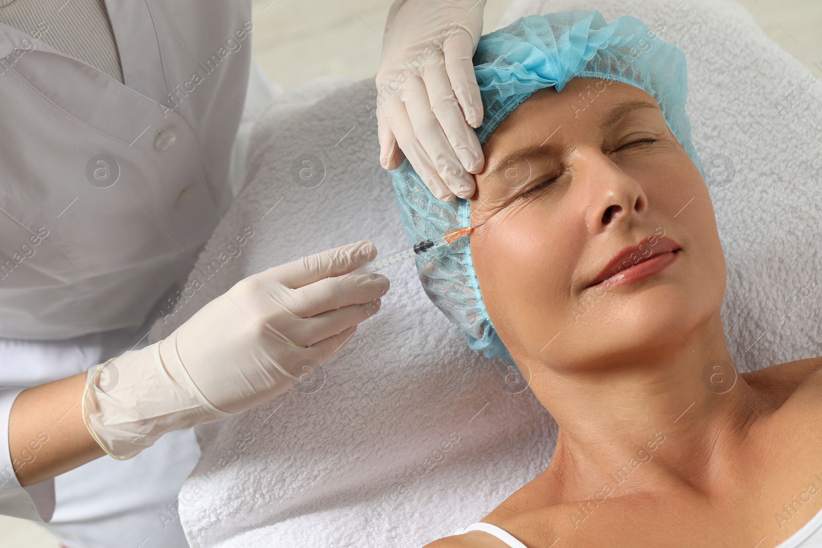 Photo of Doctor giving facial injection to senior woman in clinic. Cosmetic surgery