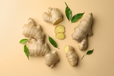 Photo of Fresh ginger with green leaves on beige background, flat lay