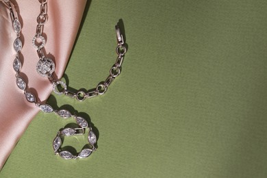 Photo of Elegant jewelry. Stylish presentation with luxury bracelets on dark green background, flat lay. Space for text