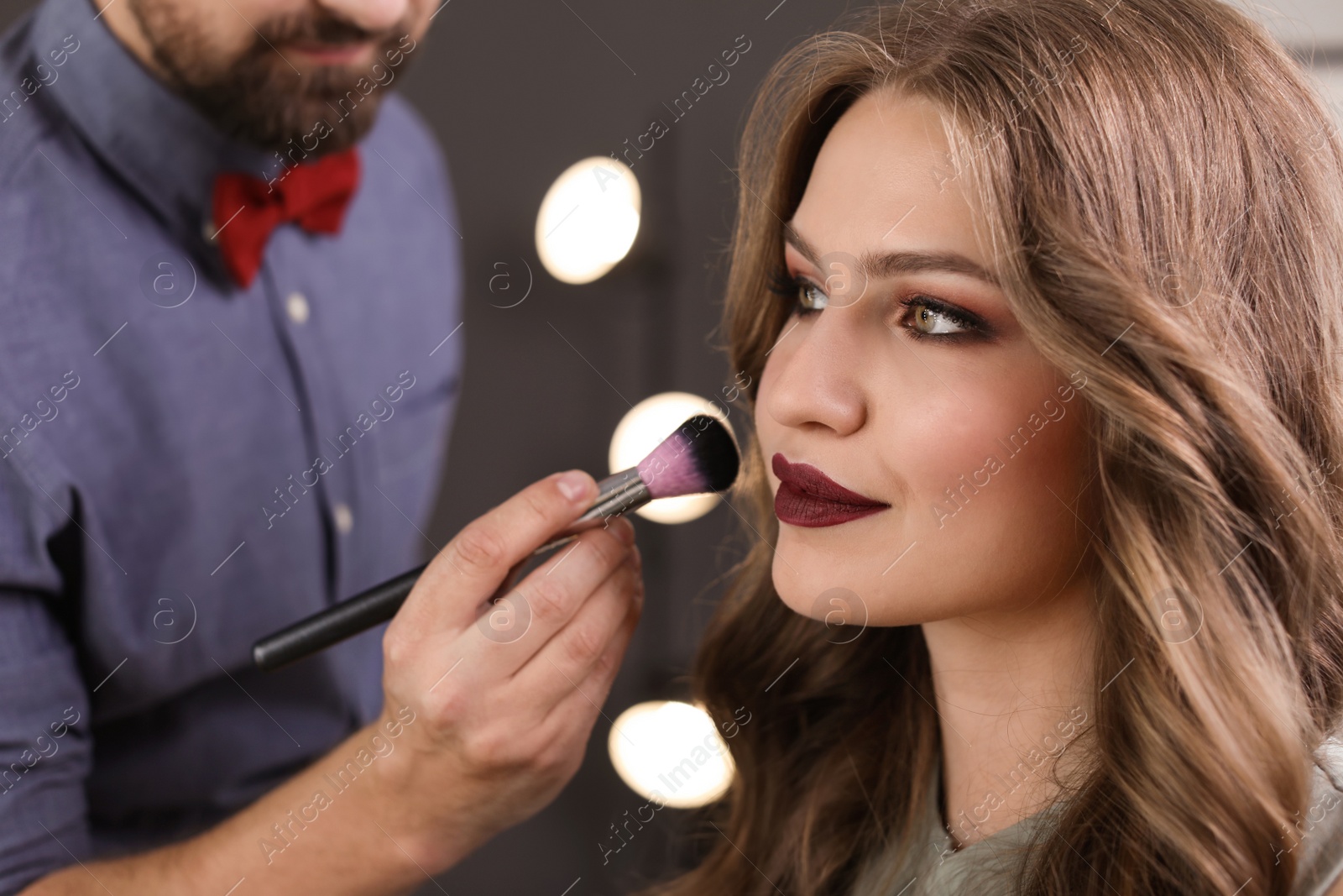 Photo of Professional makeup artist working with client in dressing room