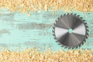 Saw disk and shavings on blue wooden background, flat lay with space for text. Carpenter's tool