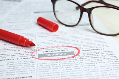 Photo of Newspaper with marked advertisement and glasses. Search concept