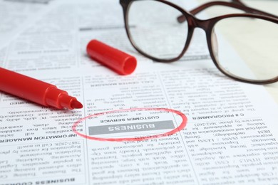 Newspaper with marked advertisement and glasses. Search concept