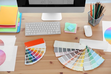 Designer's workplace with computer and paint color palette samples on table