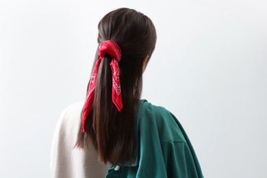 Photo of Young woman with stylish red bandana on light background, back view