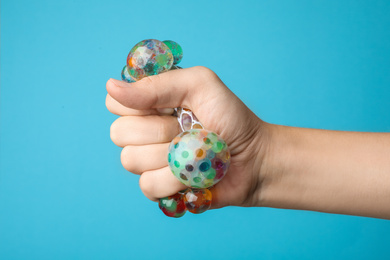 Woman squeezing colorful slime on blue background, closeup. Antistress toy