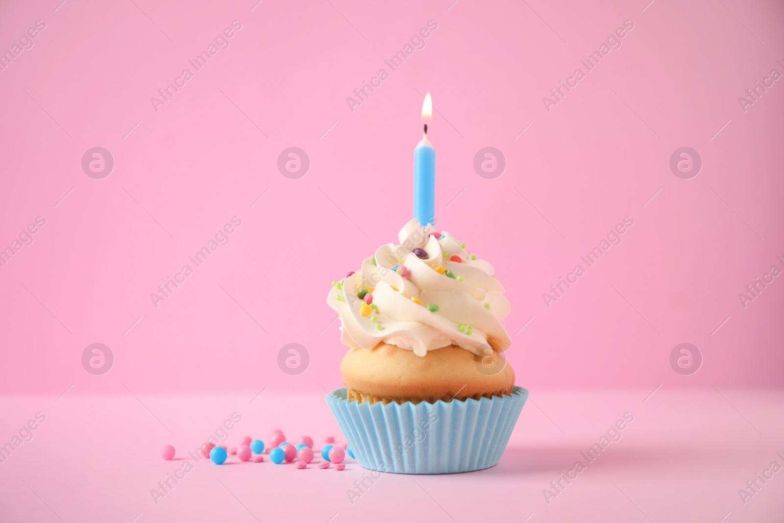 Photo of Delicious birthday cupcake with candle on pink background