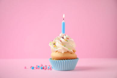 Delicious birthday cupcake with candle on pink background