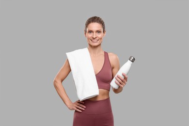Sportswoman with thermo bottle on grey background
