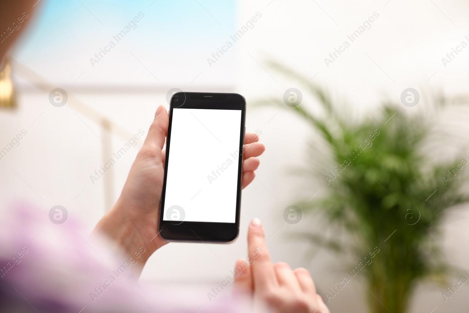 Photo of Woman holding smartphone with blank screen indoors, closeup of hands. Space for text