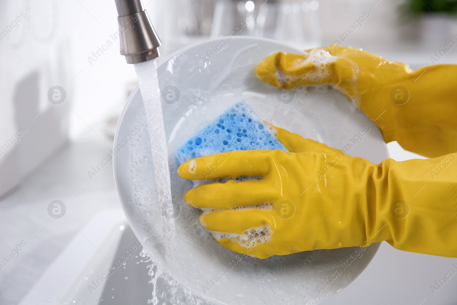 Photo of Woman washing plate in modern kitchen, closeup