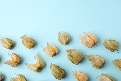 Photo of Ripe physalis fruits with calyxes on light blue background, flat lay. Space for text