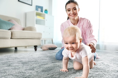 Adorable little baby crawling near mother at home