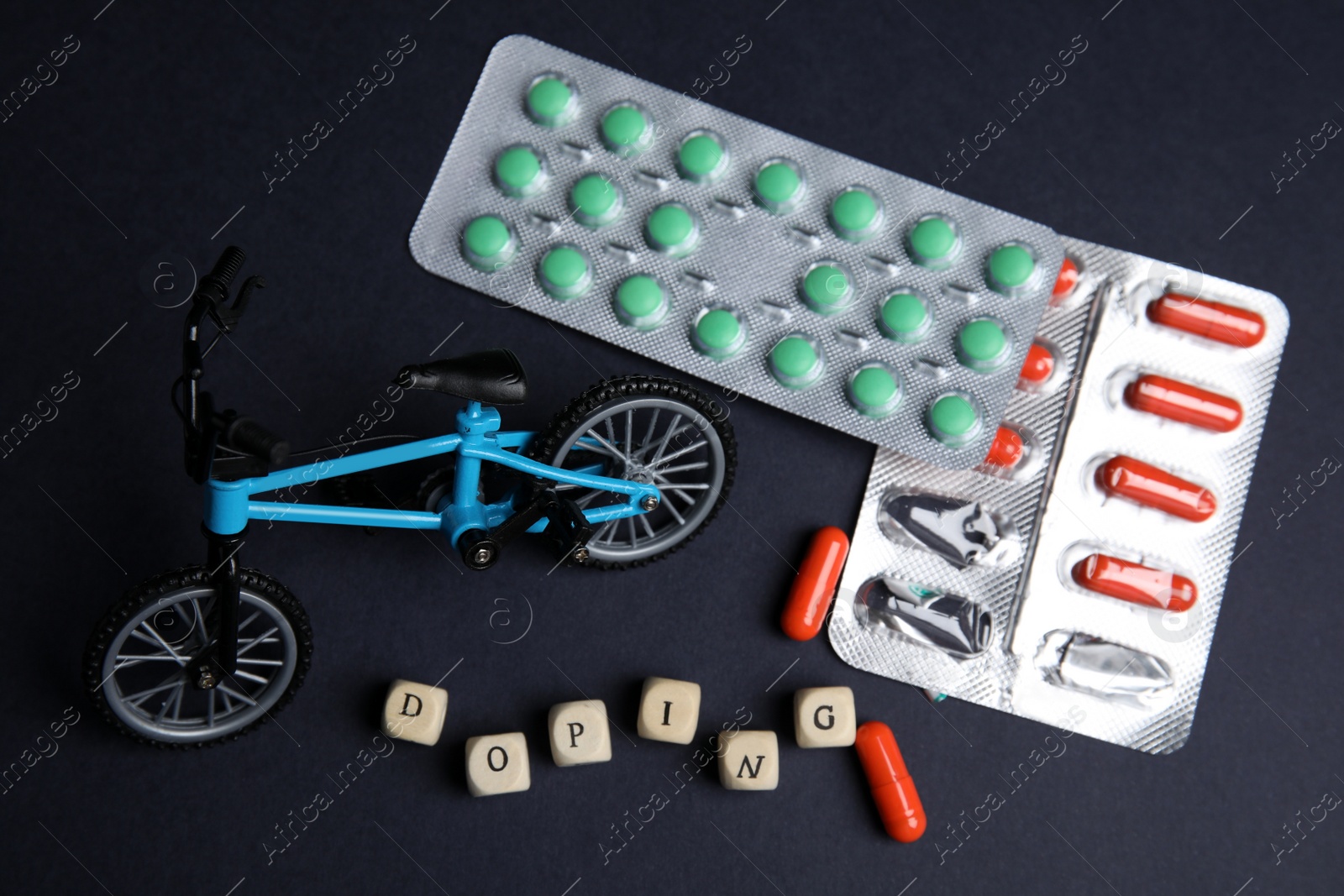 Photo of Word Doping, pills and bicycle model on black background. Flat lay