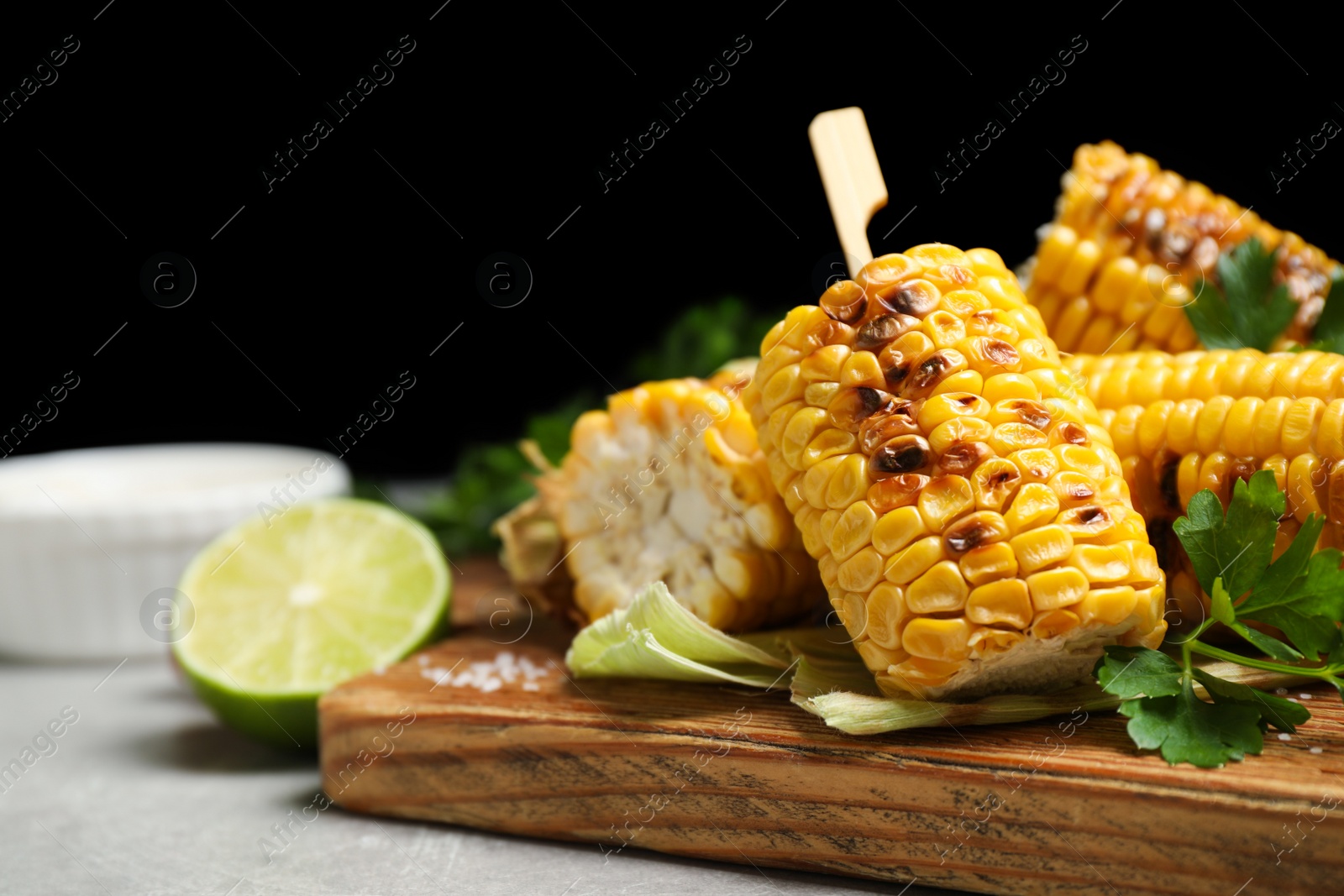 Photo of Tasty grilled corn cobs on light table, closeup. Space for text