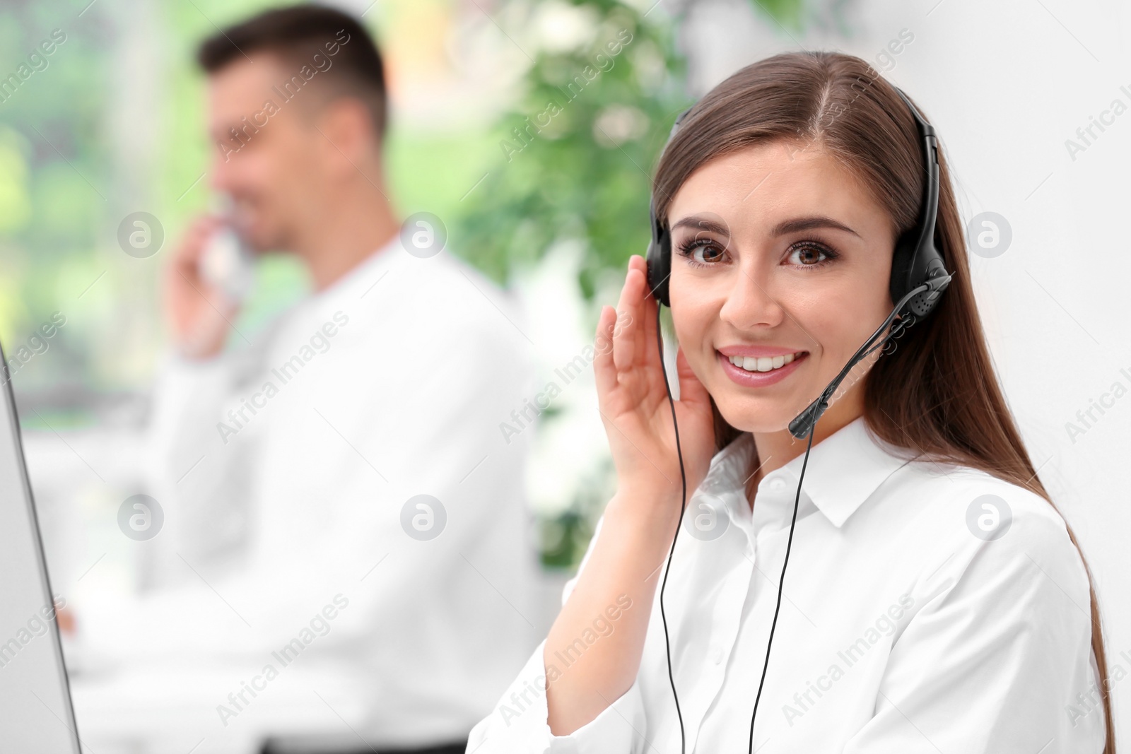 Photo of Young female receptionist with headset in office