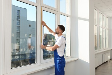 Photo of Worker measuring plastic window indoors. Installation process
