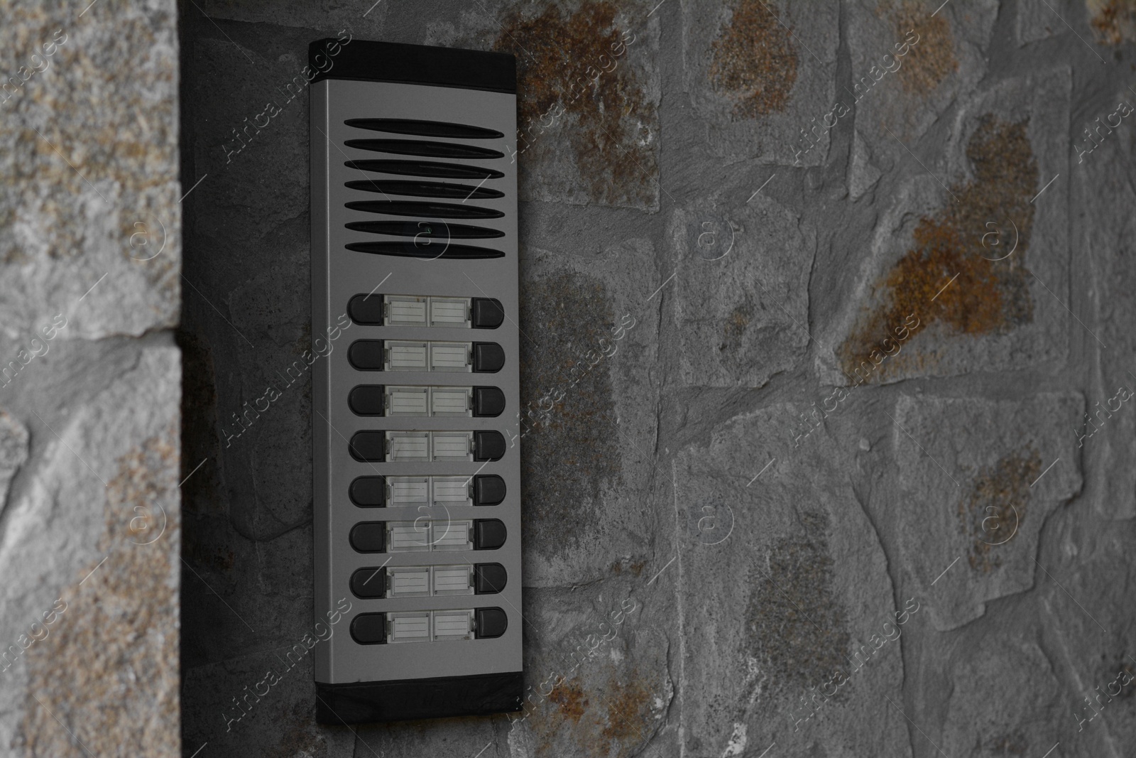 Photo of Modern intercom on concrete wall with stone fragments, space for text. Security system