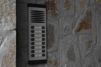 Photo of Modern intercom on concrete wall with stone fragments, space for text. Security system