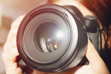 Image of Photographer with professional camera on blurred background, closeup