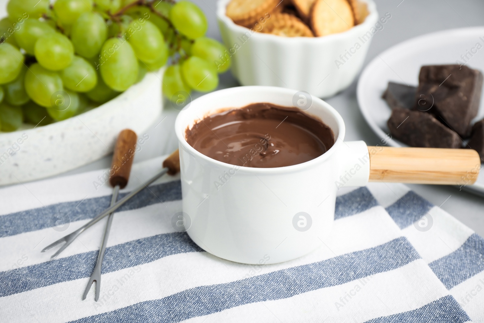 Photo of Fondue pot with chocolate and grape on table